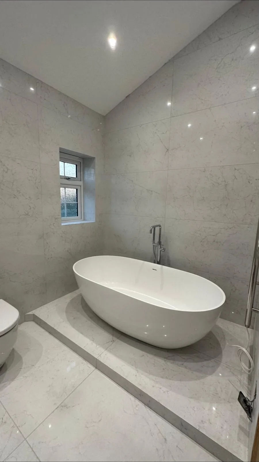 Marble tiled bathroom with a freestanding bath, fitted by TF Heating